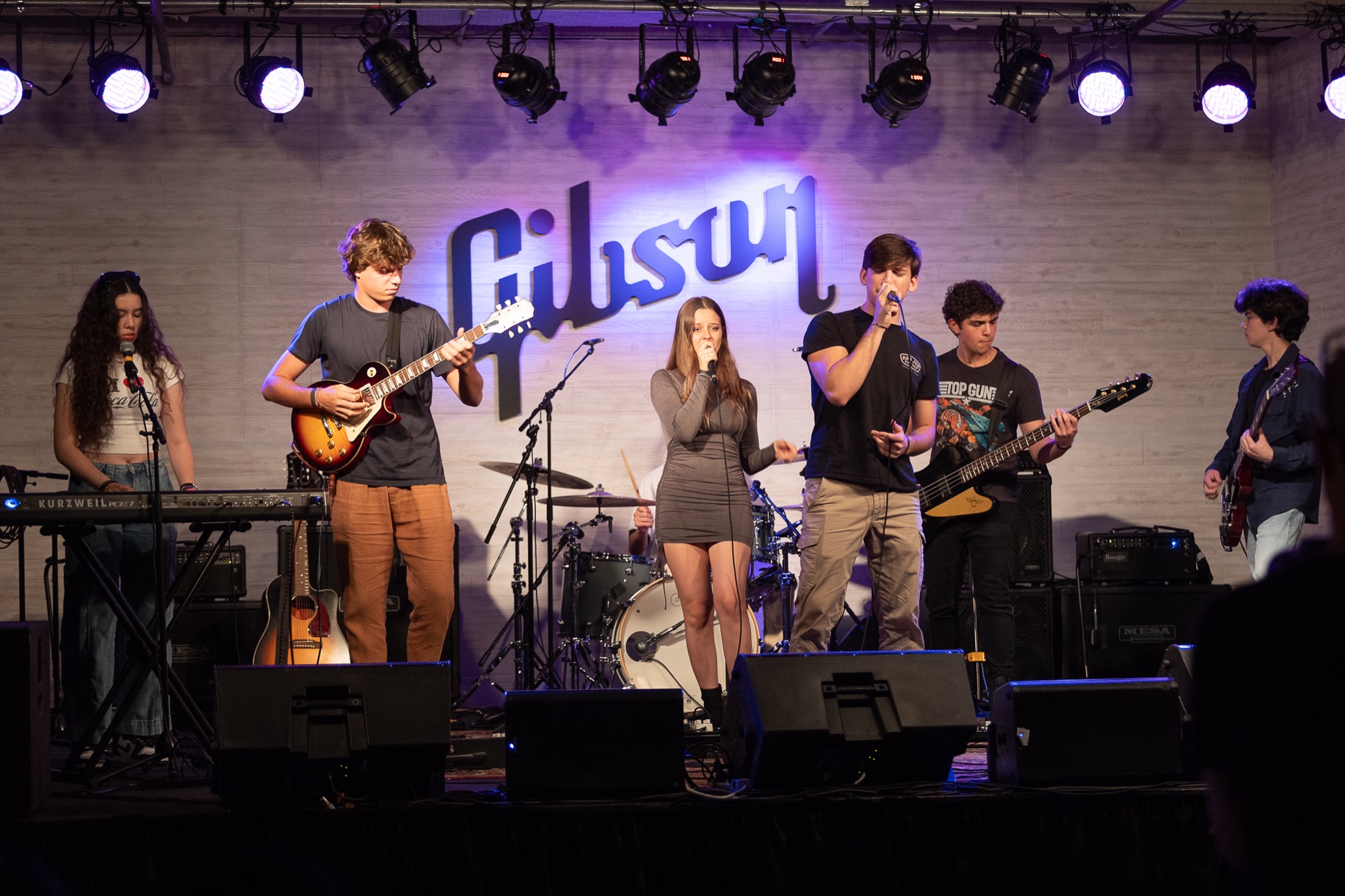 Full teen band performing under purple stage lights