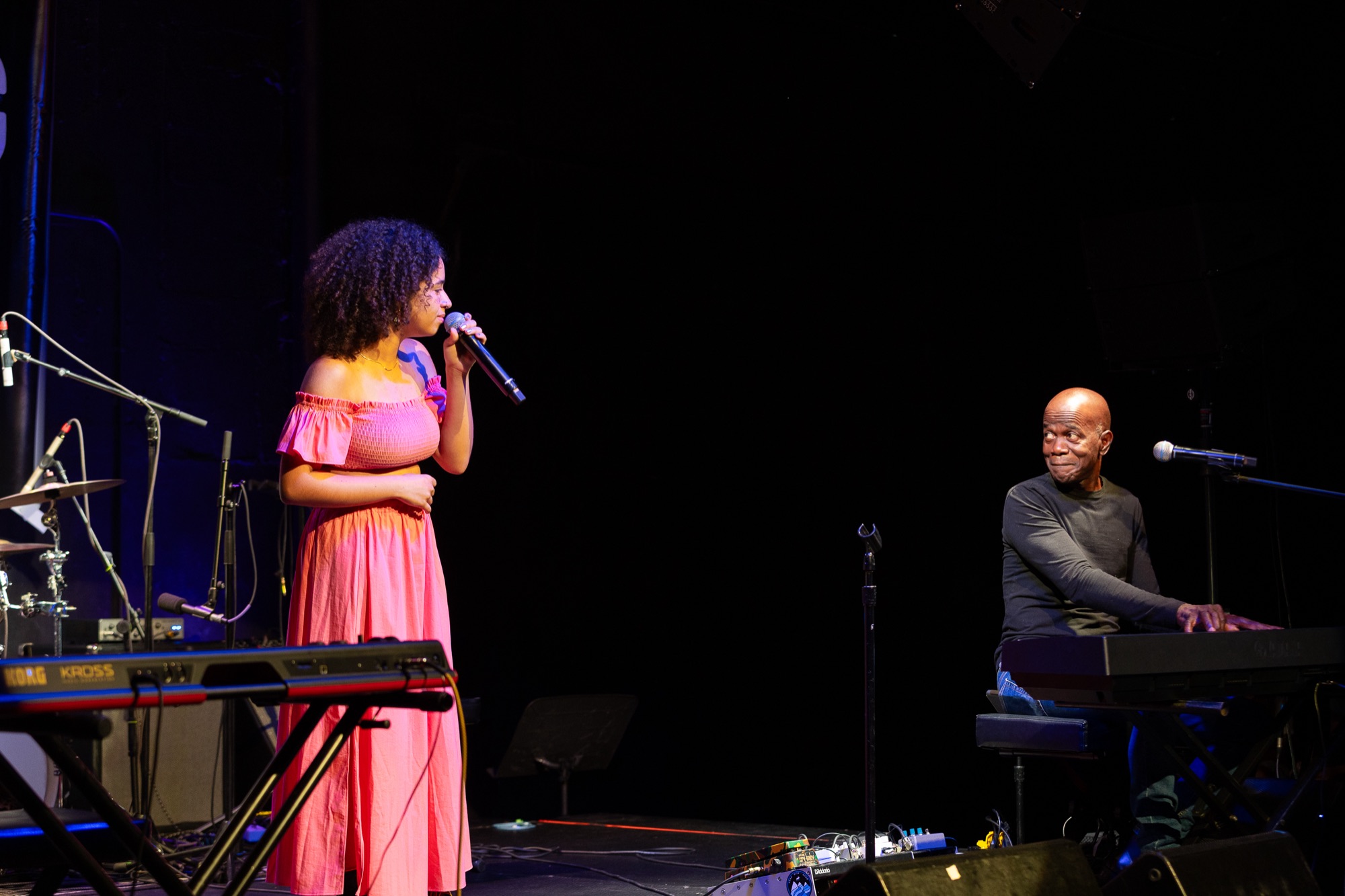 Singer in coral dress on stage accompanied by a pianist