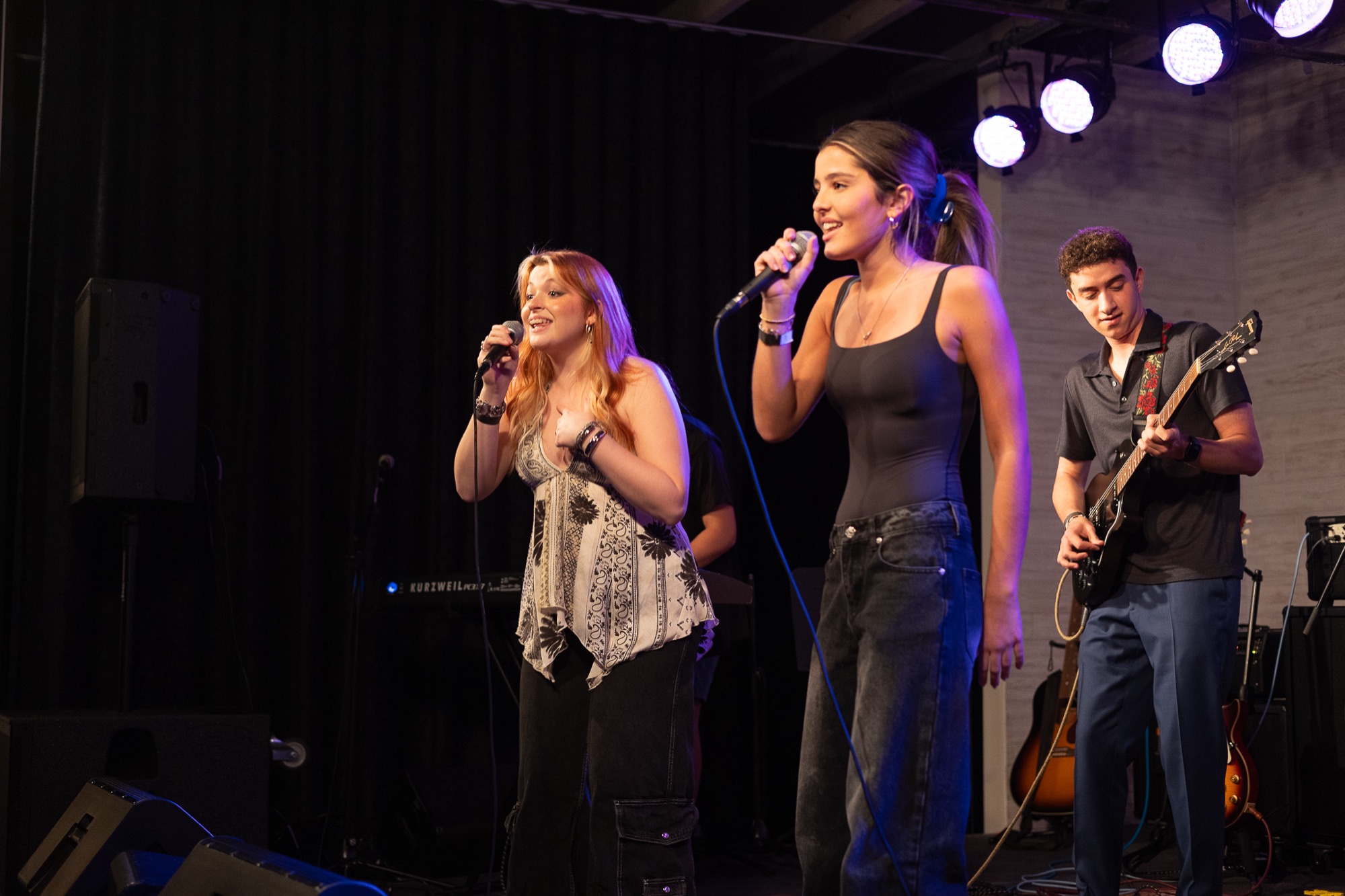 Young singer mid-song with a guitarist beside her