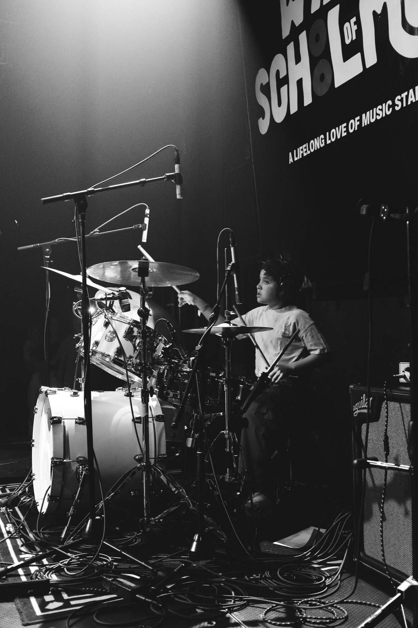Black-and-white drummer mid-fill in front of the WSM backdrop